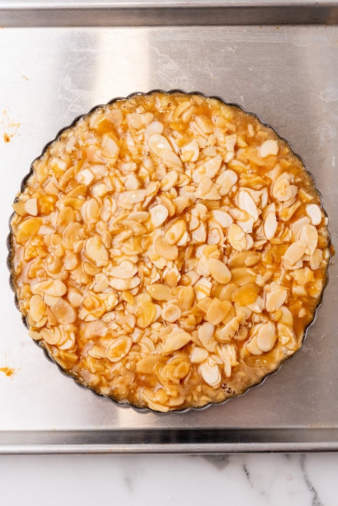 almond tart in a tart pan on a sheet pan before baking second time