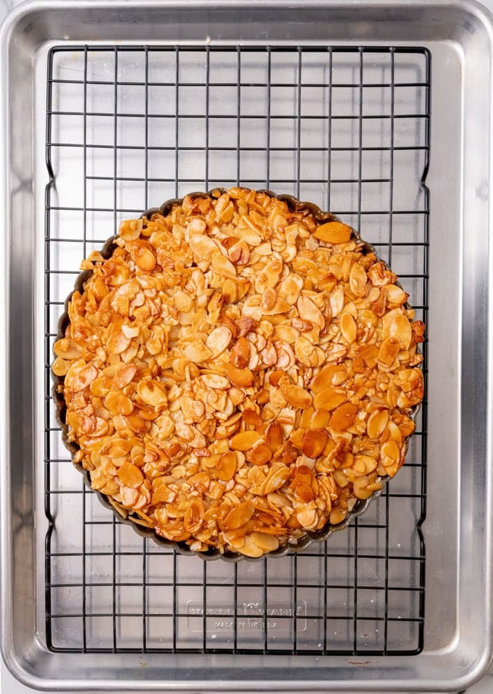 baked almond tart cooling on wire rack the top looks light brown and caramelized