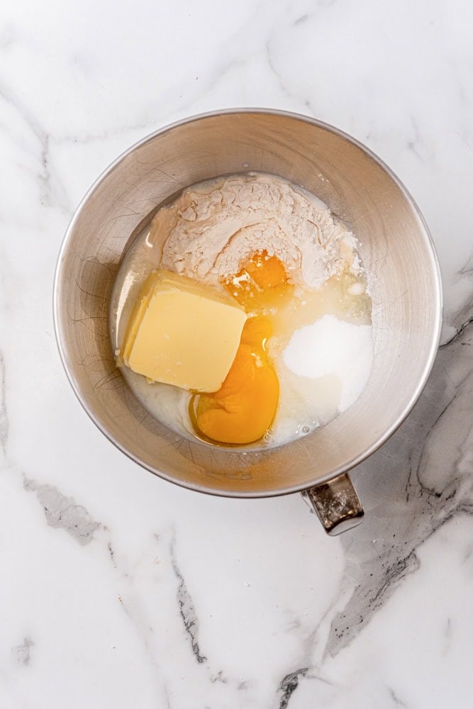Eggs, butter, flour, and sugar in a stainless steel mixing bowl