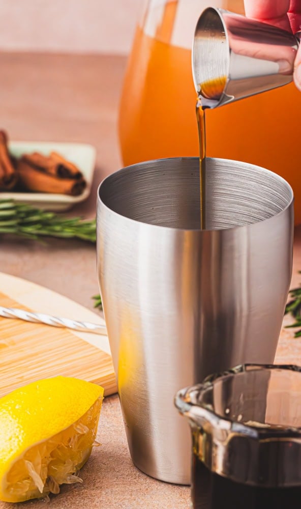 pouring maple syrup into a stainless steel shaker