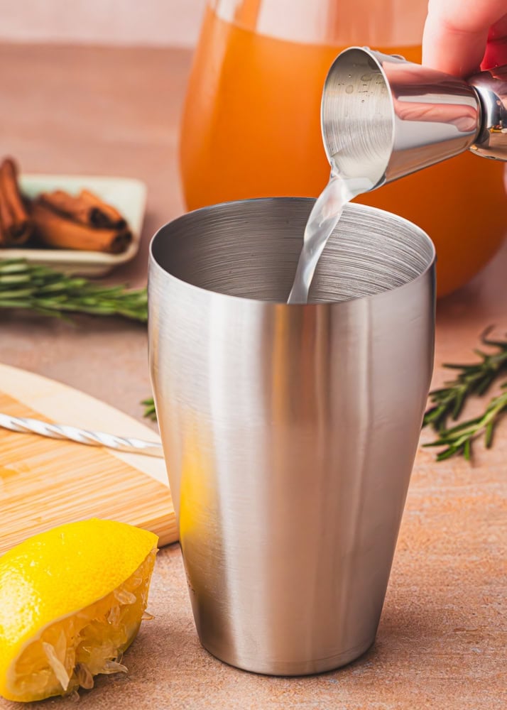 pouring lemon juice into a stainless steel shaker