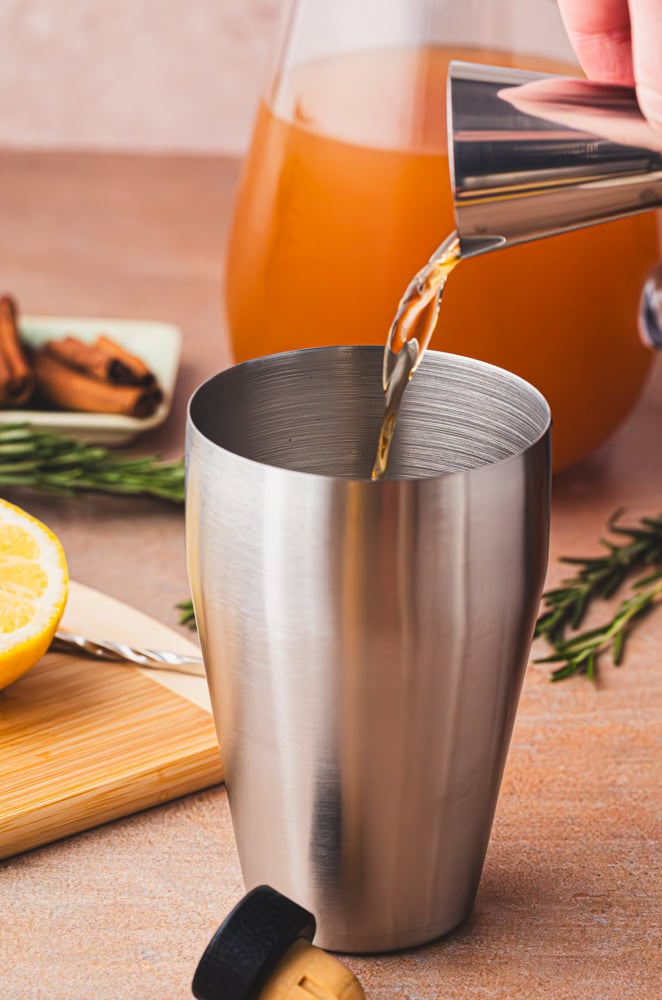 pouring bourbon into a stainless steel shaker