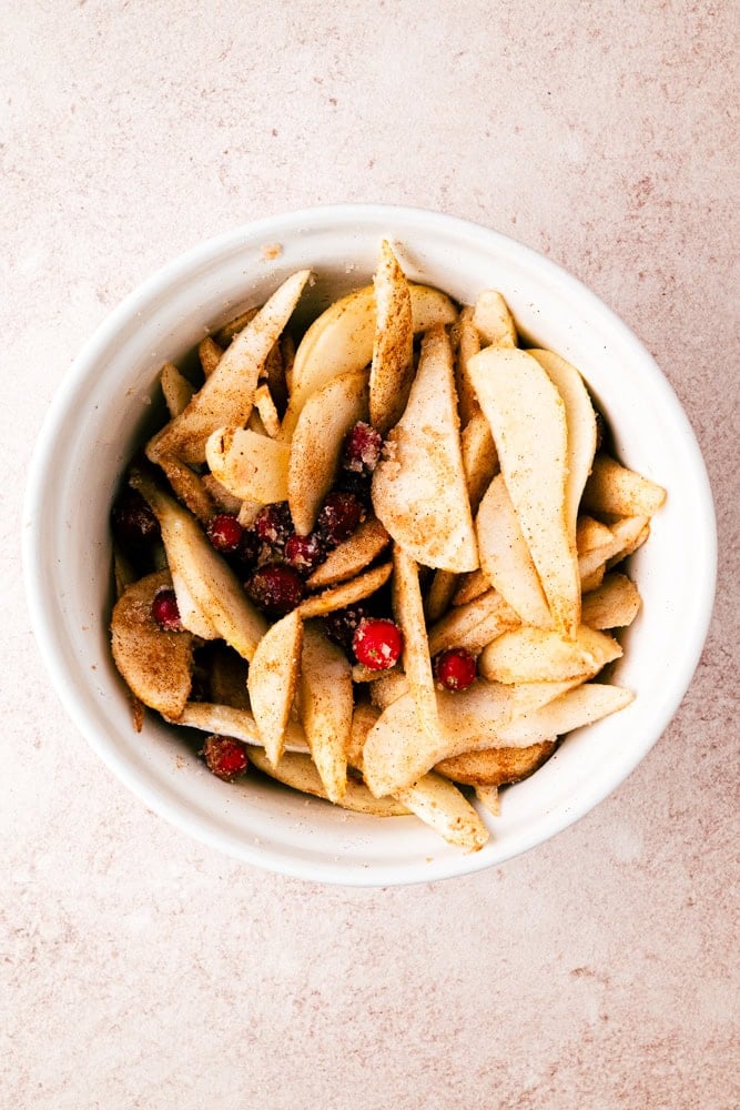 bowl with sliced pears, cranberries, and spices