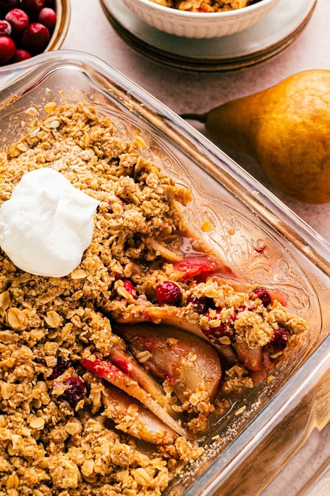 light pink square banking pan with pear crisp with cranberries inside