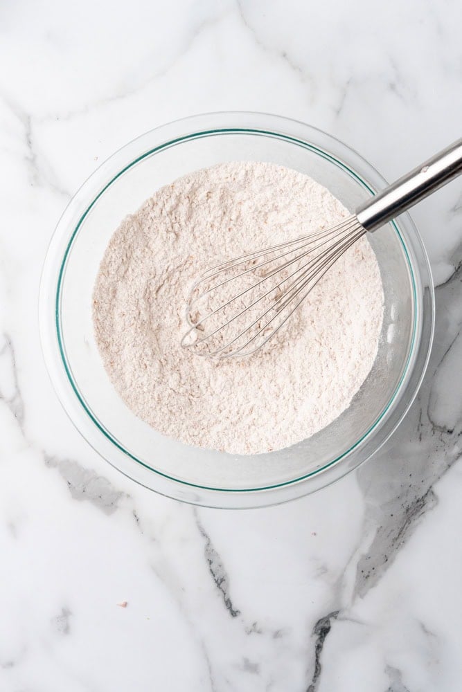dry ingredients for whole wheat biscuits in glass bowl mixed together with whisk