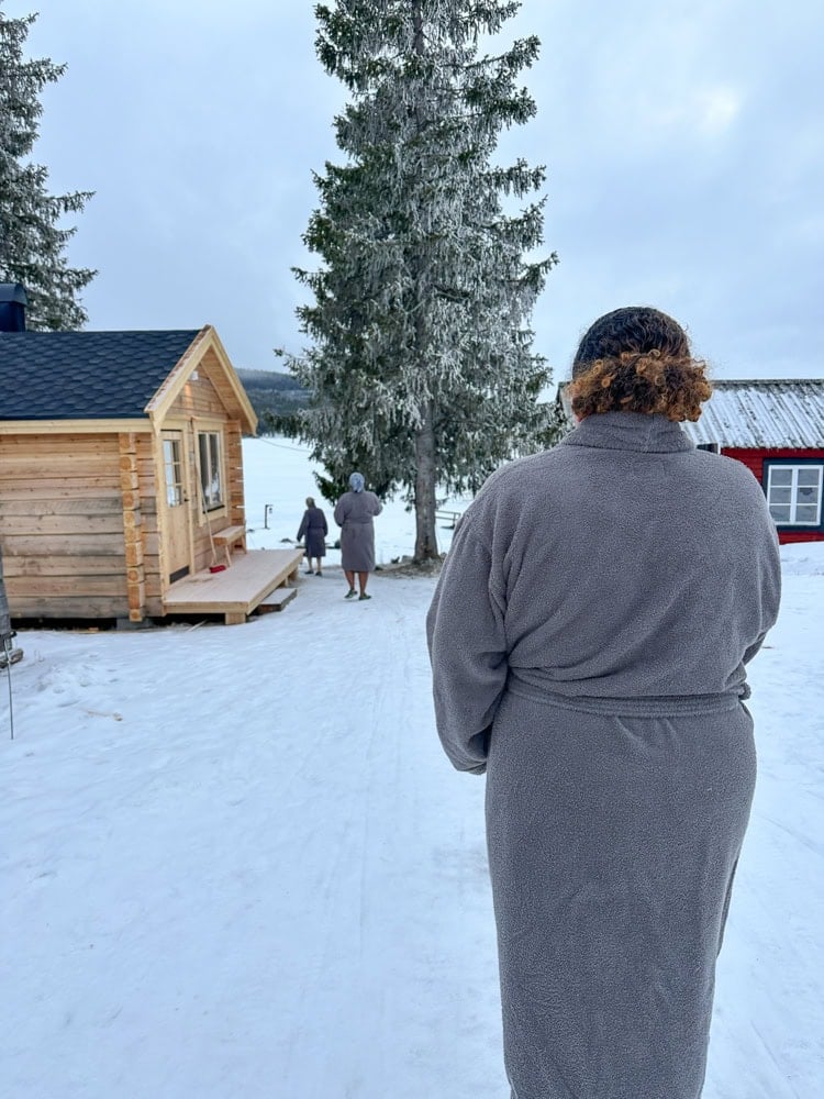 wearing robes and walking to the Torne River outside the ice hotel