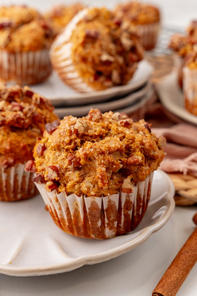 fresh baked sweet potato muffin on a plate with more muffins in the background