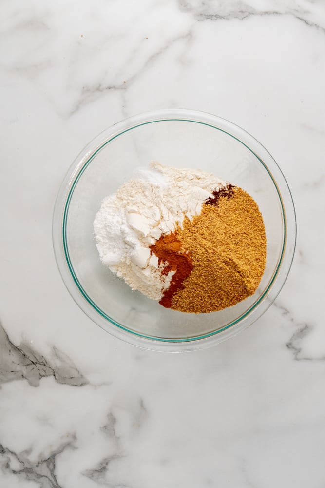 spices and flour in a clear glass bowl before mixing