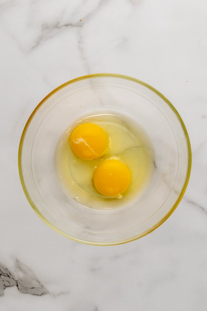 two raw eggs in a clear glass bowl