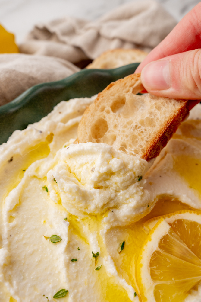 Scooping whipped ricotta dip onto a crostini
