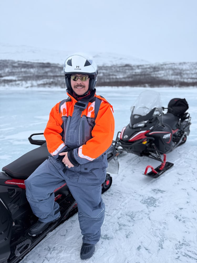 Pete posing and half sitting on snowmobile