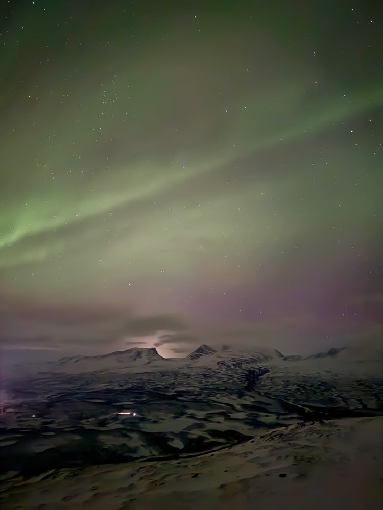 pink and green aurora over a mountain
