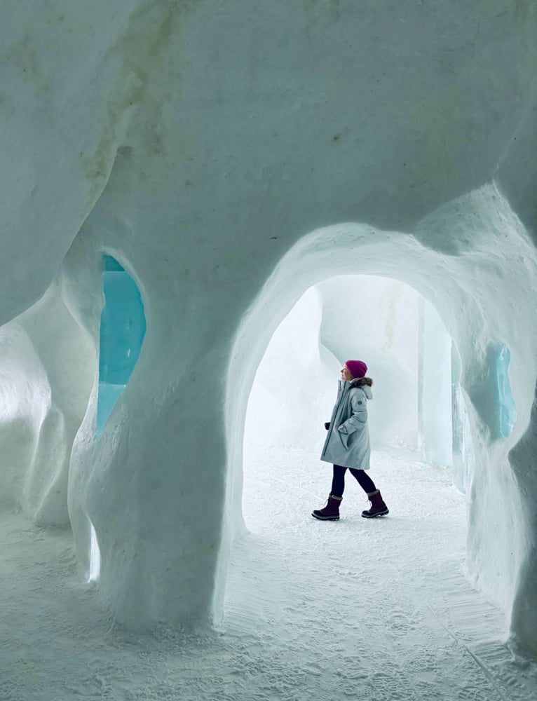 Rachelle walking through the cavernous cafes in the ice hotel. The colors are white with snow and deep turquoise blue with the ice.