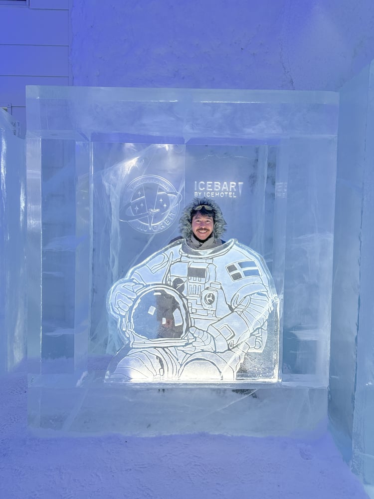 Pete posing in an ice sculpture of an astronaut at the Ice Hotel
