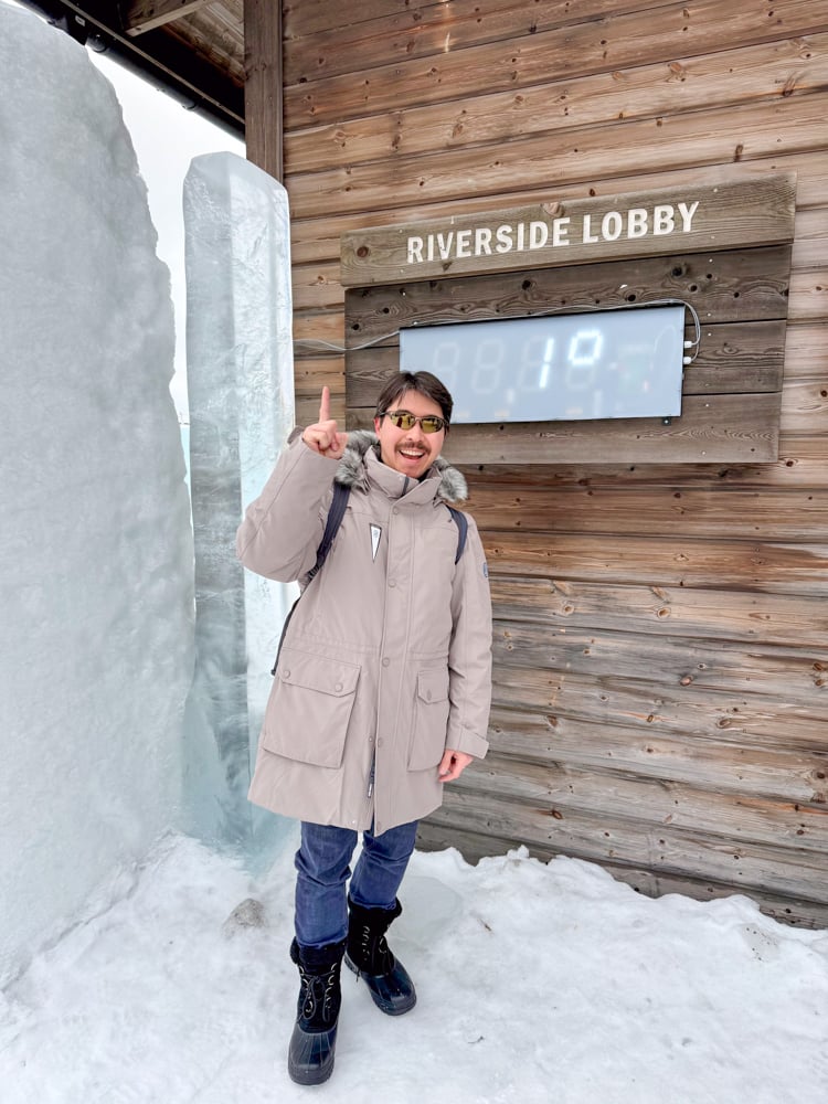 Pete pointing to the outside temperature of 1 degree by the Riverside Lobby at the Ice Hotel.