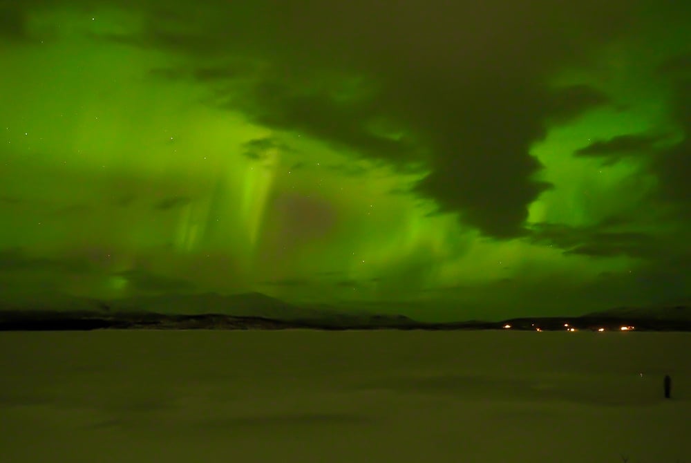 Bright green aurora over a frozen lake