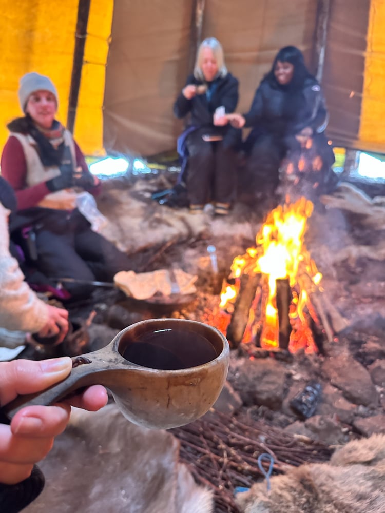 Sipping hot juice out of a mug next to a fire pit