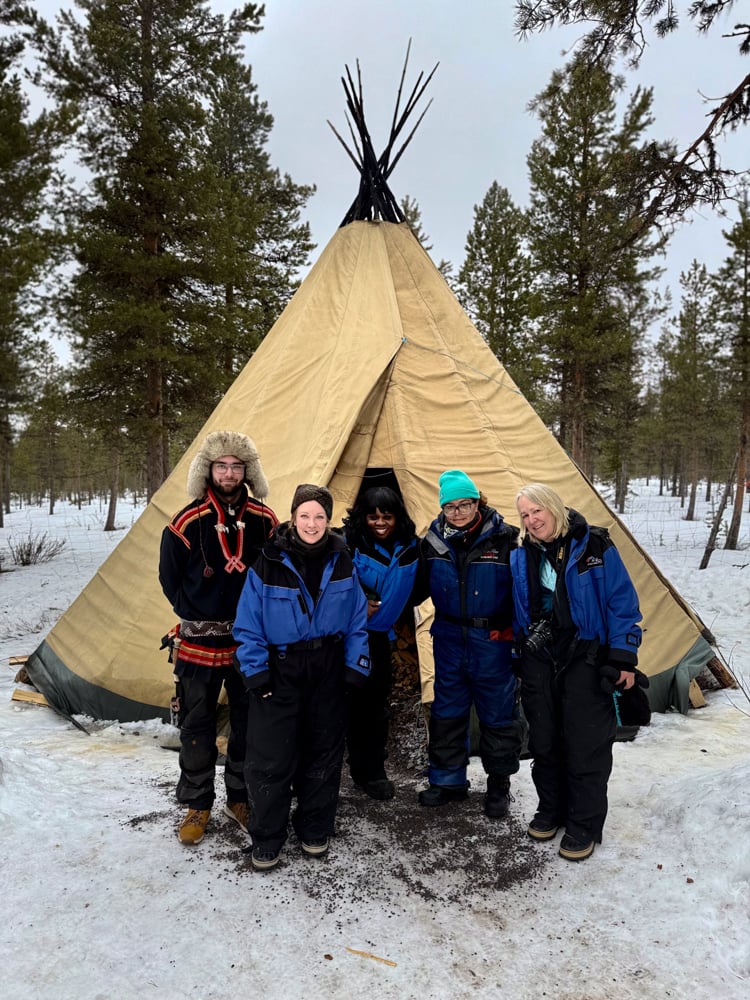 Group of people from tour standing outside a teepee