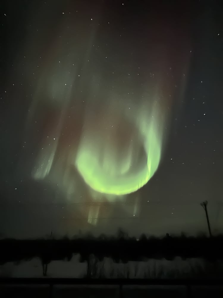 swirl of northern lights in a circle above power lines