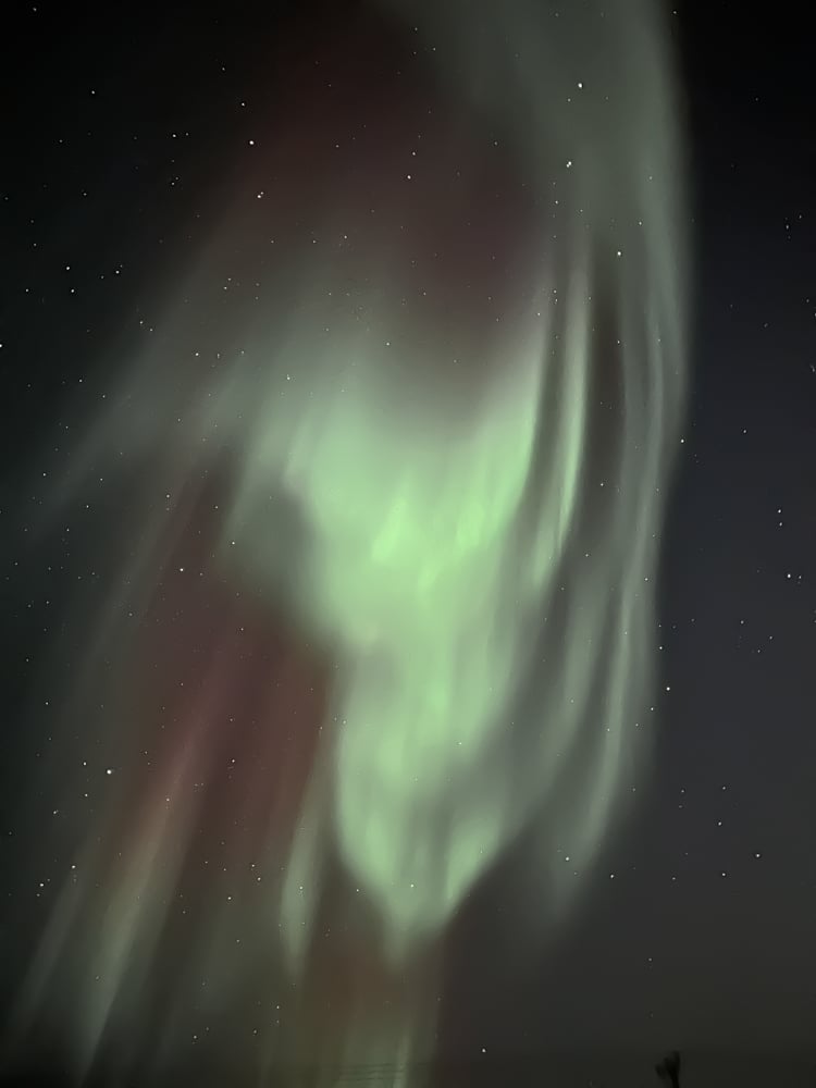 a wave of light green and red northern lights in the shape of an upside down triangle