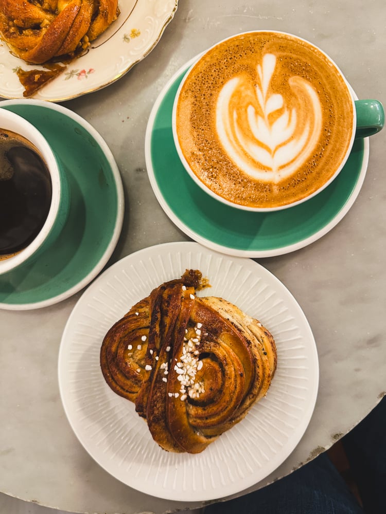 coffee in a teal mug and a cinnamon bun