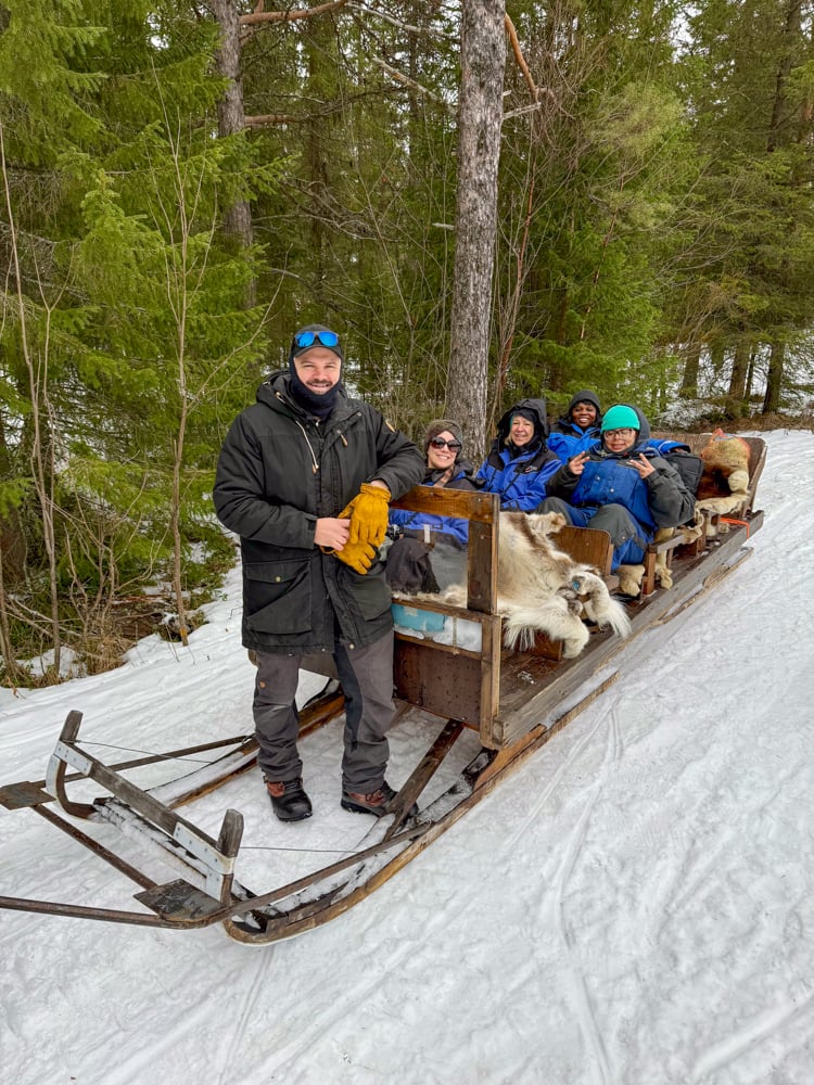 Corey on the front of a sleigh with our tour group.