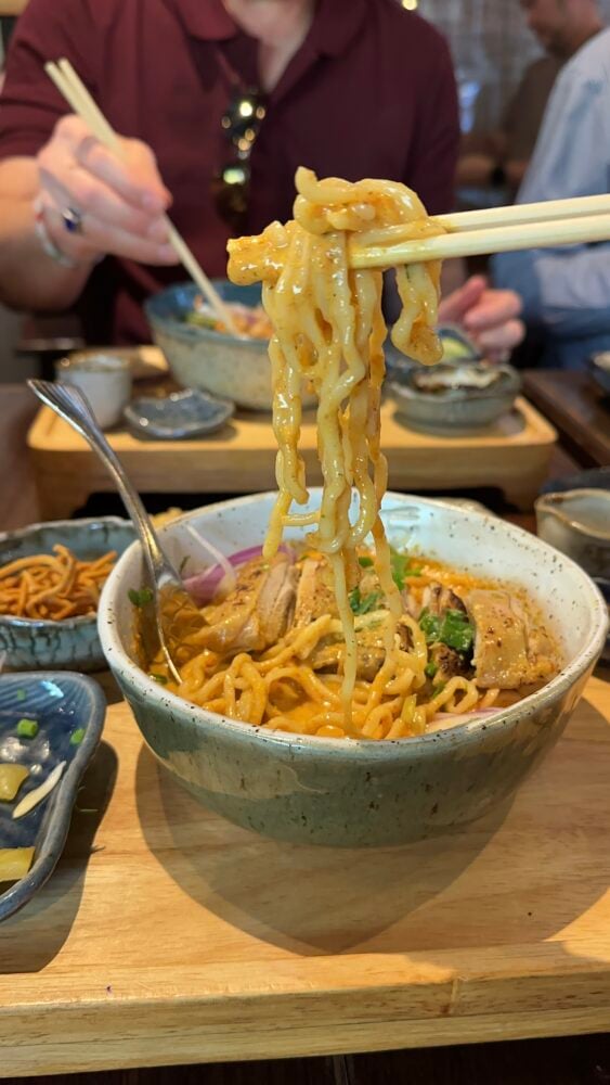 chopsticks holding noodles of Thai curry