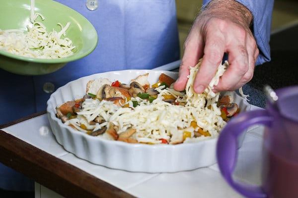 Chef Jim's hands layering in cheese on top of pulled bread and sautéed veggies