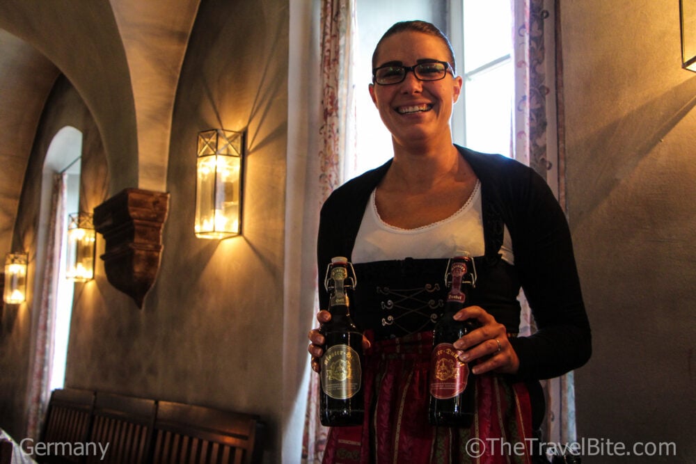 Server in traditional German costume with two bottles of beer