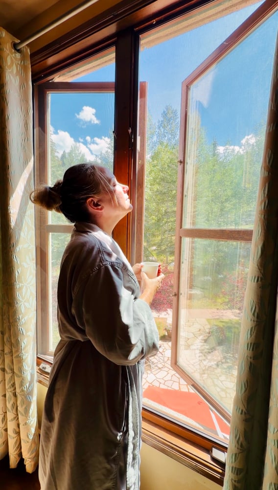 Rachelle looking out a window holding tea at the spa