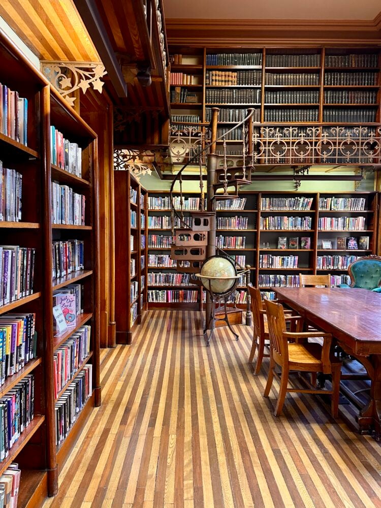 inside the library of St Johnsbury Athenaeum showing striped floors, a globe, and spiral staircases