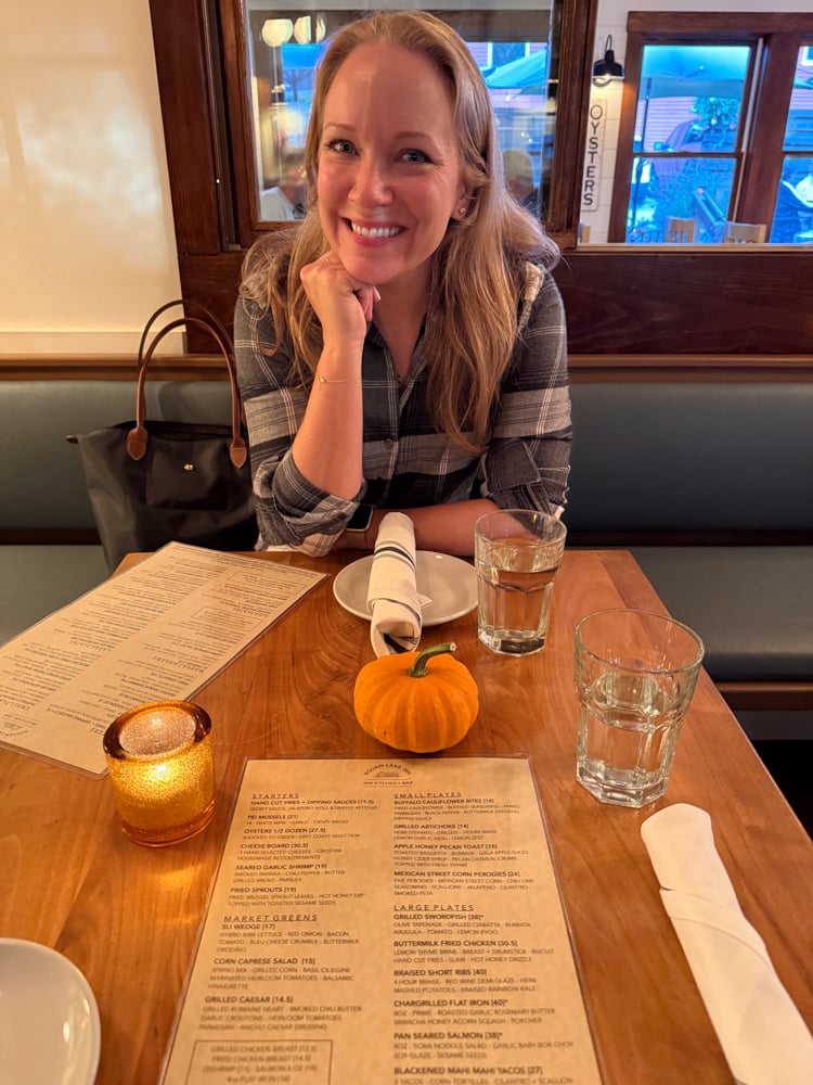 Rachelle sitting at dinner with a menu and mini pumpkin in front of her