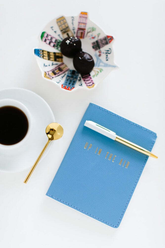 coffee cup with blue journal and chocolates in a Paris themed dish